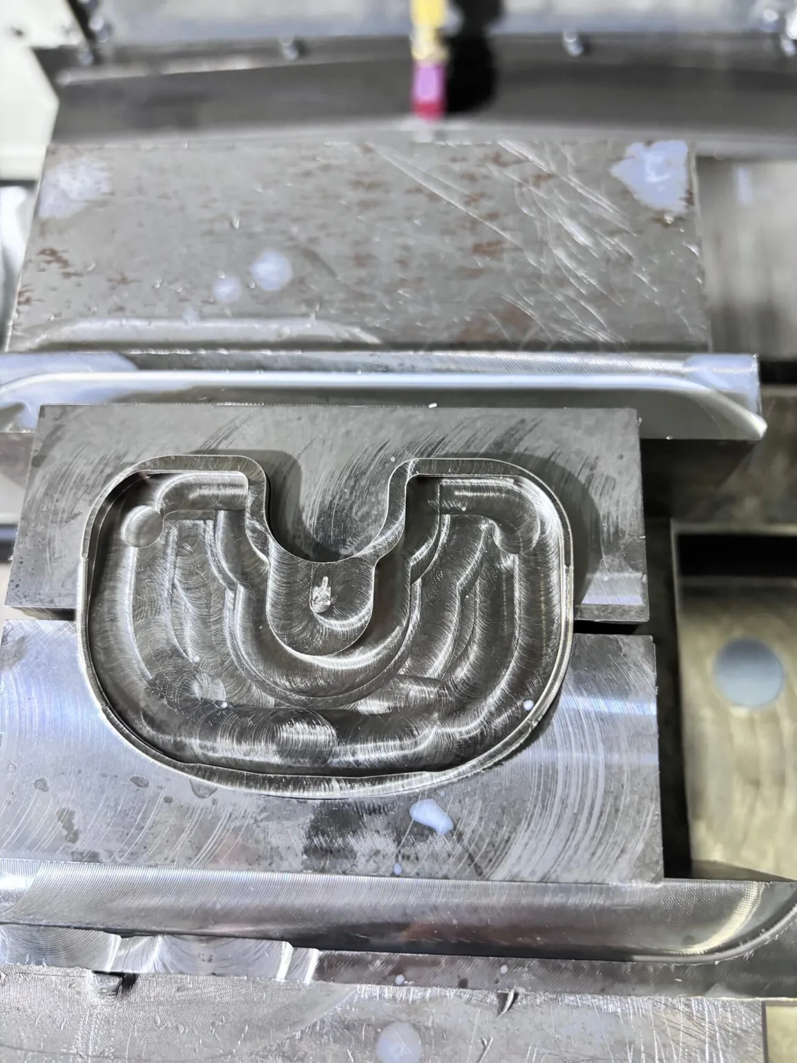 CoCrMo tibia component mold after milling, with end-mill marks across the flat surface and cavity floor